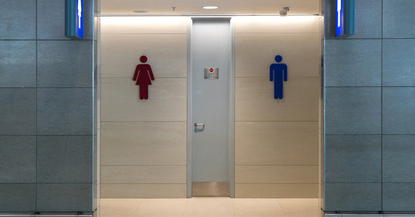 A view of the entrance to a set of men's and women's public restrooms from a hallway inside a commercial building.