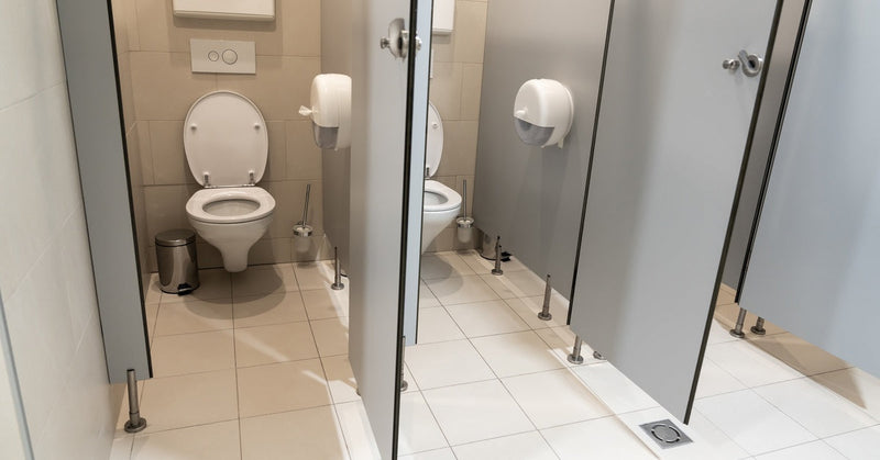 A pair of public restroom stalls with open doors. There are toilet seat cover dispensers on the back walls.